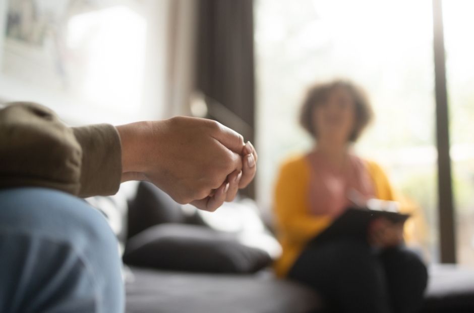 Conversa em um consultório, com as mãos de uma pessoa em primeiro plano
